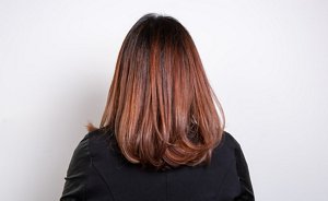 Woman with dark auburn hair blown-out in a professional way 